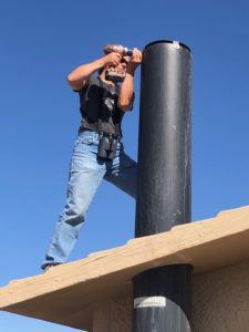 A volunteer for the Poo-Poo Project installs a screen on a vault toilet pipe.
